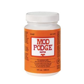 A white tub with an orange label with a white box that says 'mod podge' in pink lettering, with black lettering on the orange label