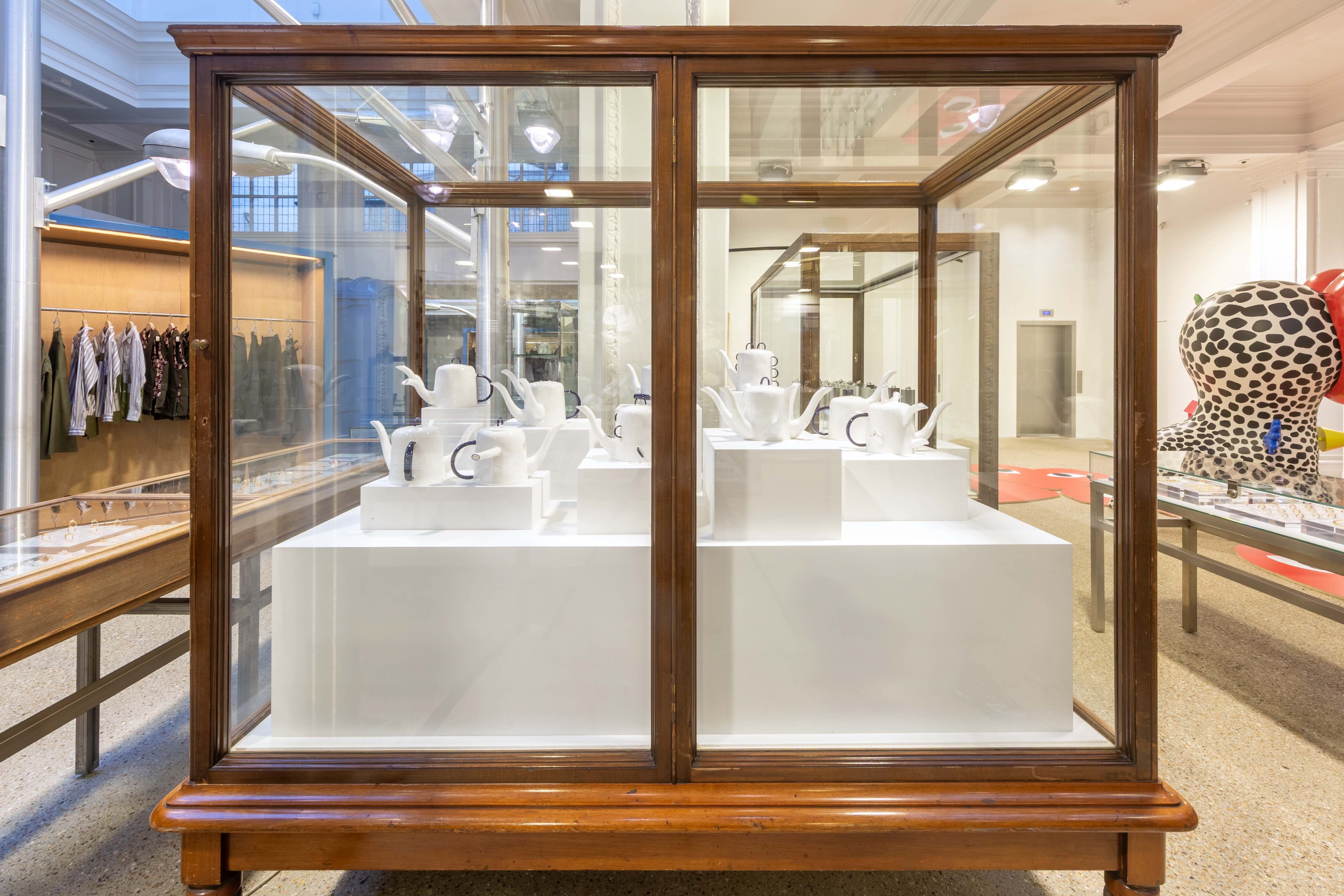 white bone china teapots with blue handles in glass vitrine