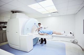 A nurse prepares a patient for an MRI.
