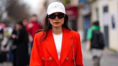 best spf moisturisers - Fer Millan wears a white cap, sunglasses , a white top, a bold red oversized blazer jacket 