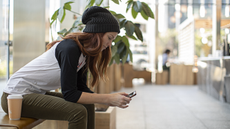 Young woman on her phone sitting on a bench