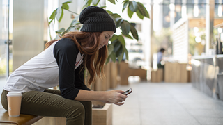 Young woman on her phone sitting on a bench