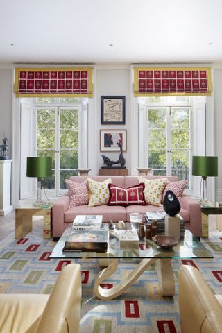 Smart living room with pink sofa and a coffee table in front of two windows, with bold red square print throughout.