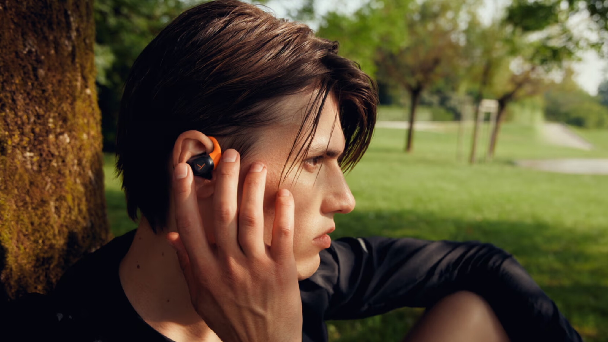 A young man with dark hair wearing a pair of Beyerdynamic Amiron 200 earbuds
