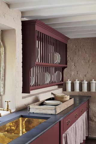 A country kitchen with a traditional plate rack painted in Devol's Refectory Red