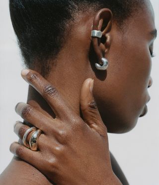 Two silver ear rings on ear.