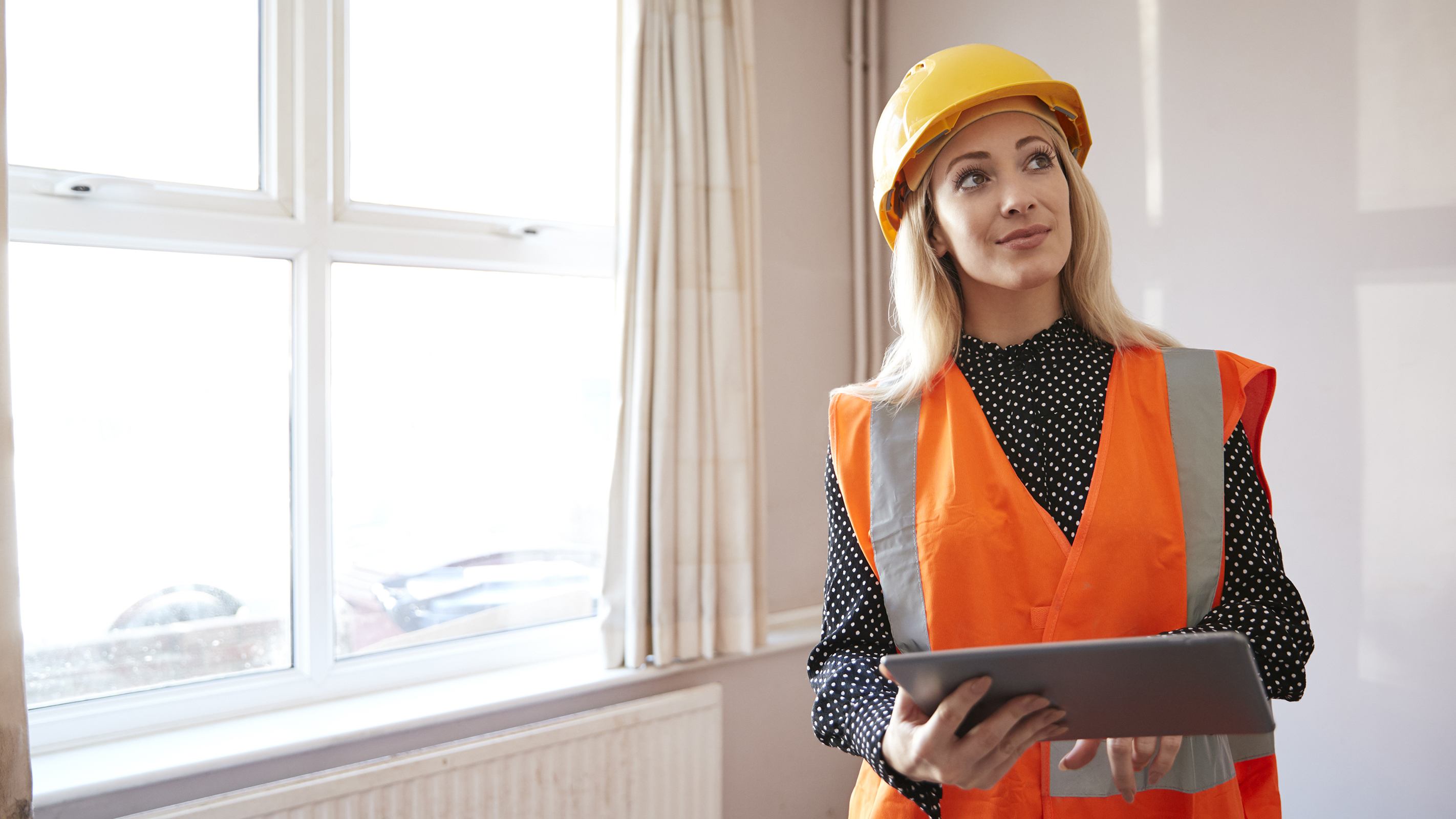 female building surveyor in house with clipboard