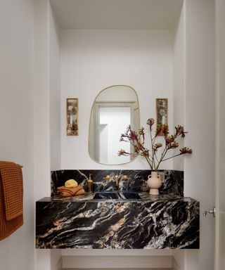 powder room with black veined marble vanity and backsplash