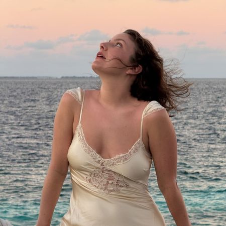 A photo of @emmahoareau by the sea wearing a cream dress