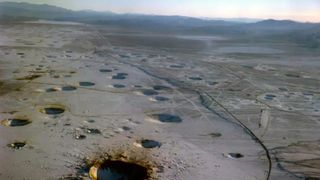 The testing site in Navada used during Operation Plumbbob. We see a desert filled with large holes.