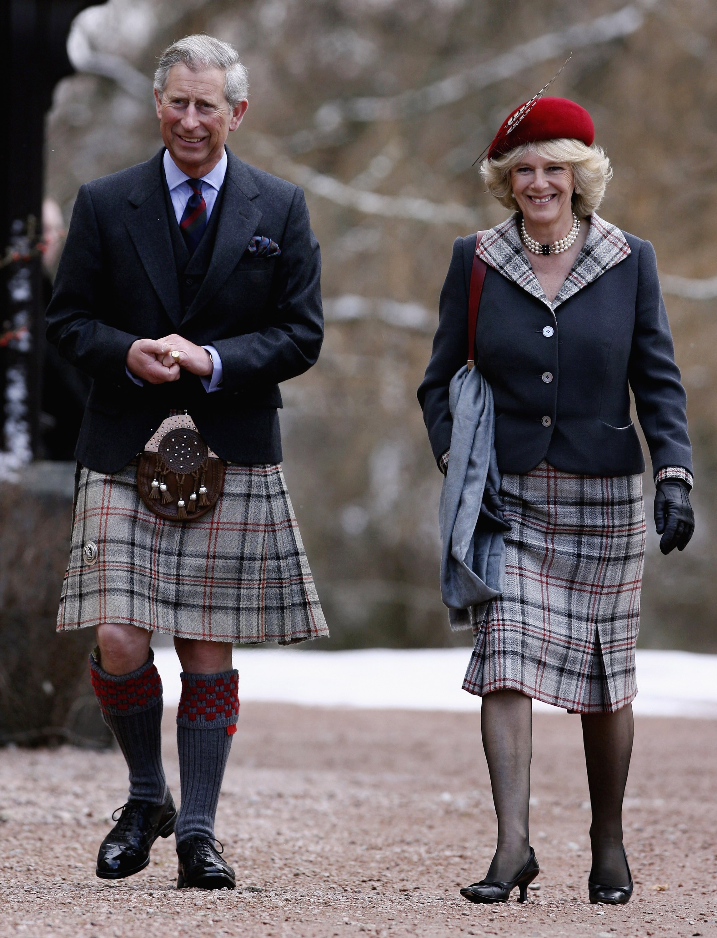 King Charles and Queen Camilla walking next to each other wearing coordinating tartan outfits