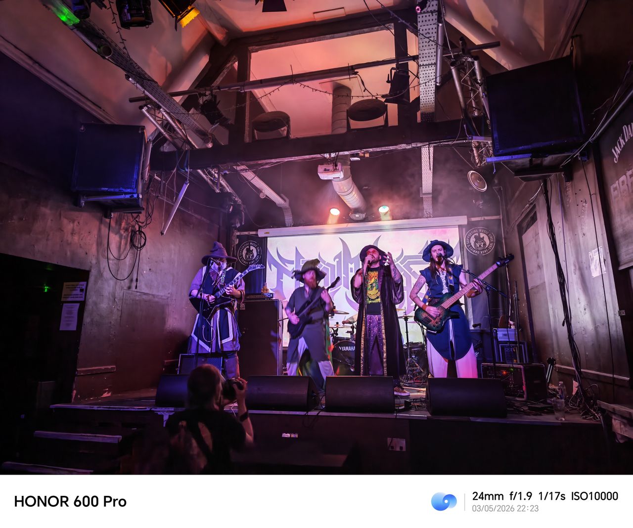 Wide shot of a band performing on a small stage under colorful lighting