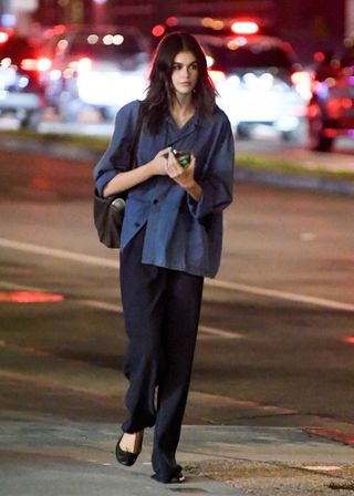 A photo of Kaia Gerber accessorizing her solo dinner date ensemble with black Repetto ballet flats and a black cargo tote bag.