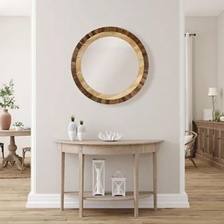 A circular mirror hanging on a white wall above a console table