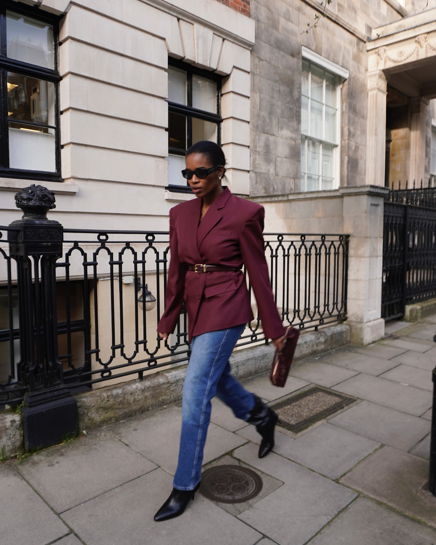 Woman wearing a blazer with a belt layered over it.