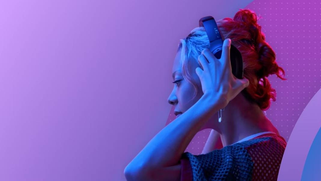 A side profile of a woman putting a pair of headphones over her ears