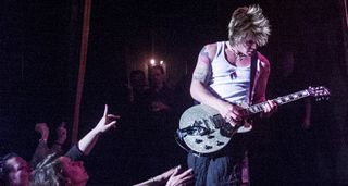 Goo Goo Dolls' John Rzeknik plays a silver sparkle singlecut guitar onstage in 1999