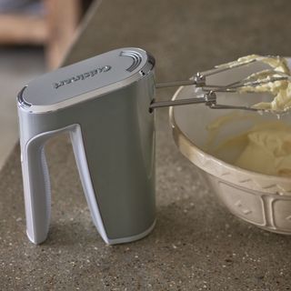 grey hand mixer mixing ingredients in a white bowl