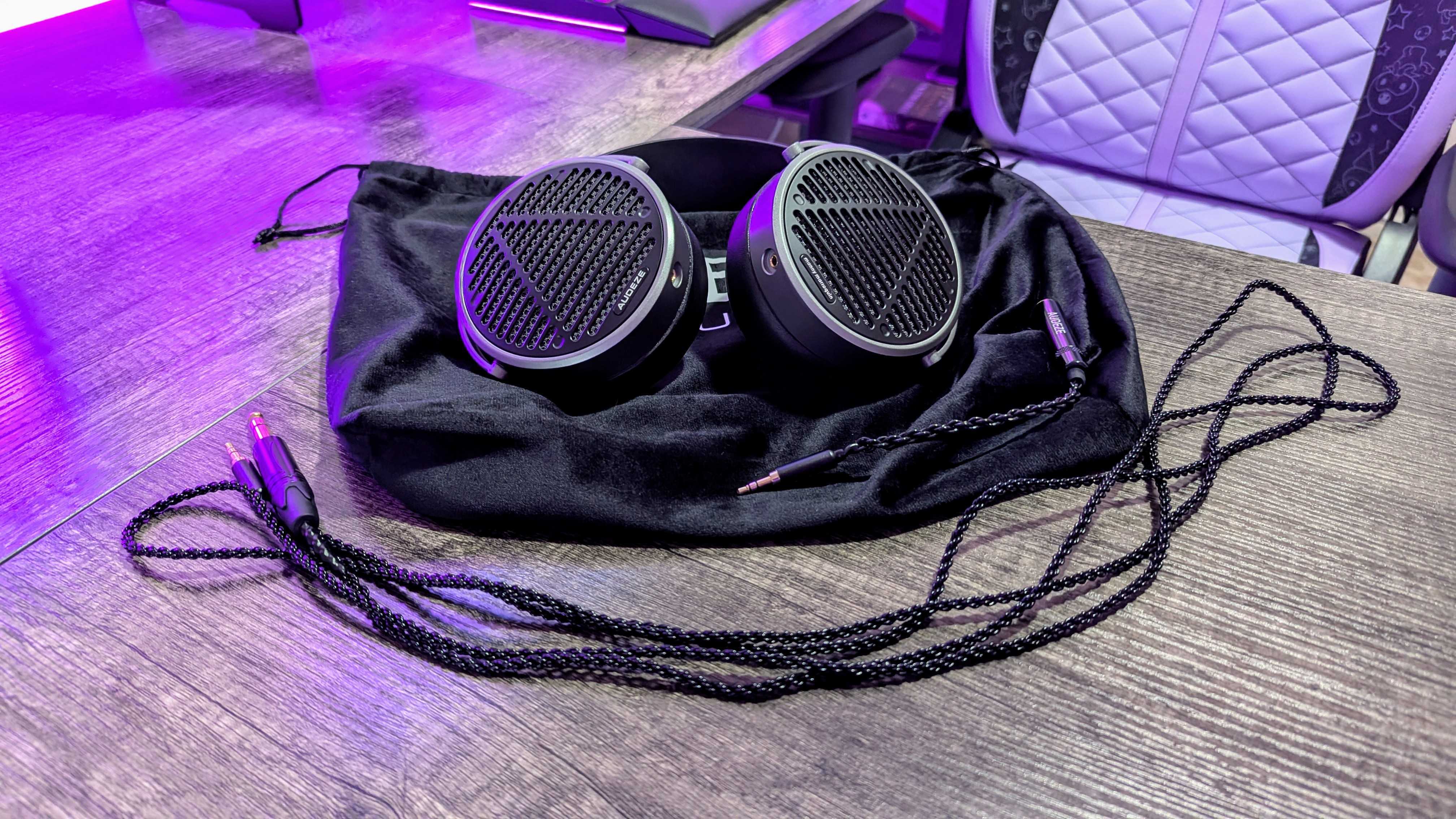 The Audeze MM-100 on a desk, lying on its soft travel cover with its cable and cable adapter in front of it.