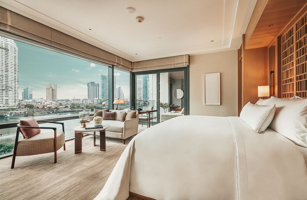 Bedroom in neutral tones with full length windows looking out over the city