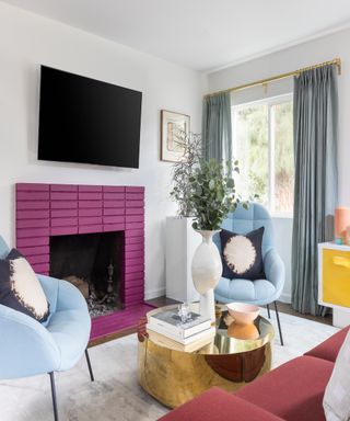Purple tiled fireplace hearth in modern living room with duck egg blue chairs, a gold coffee table, blue drapes and modern white vase