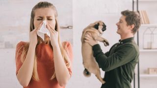 Woman sneezing dog in background