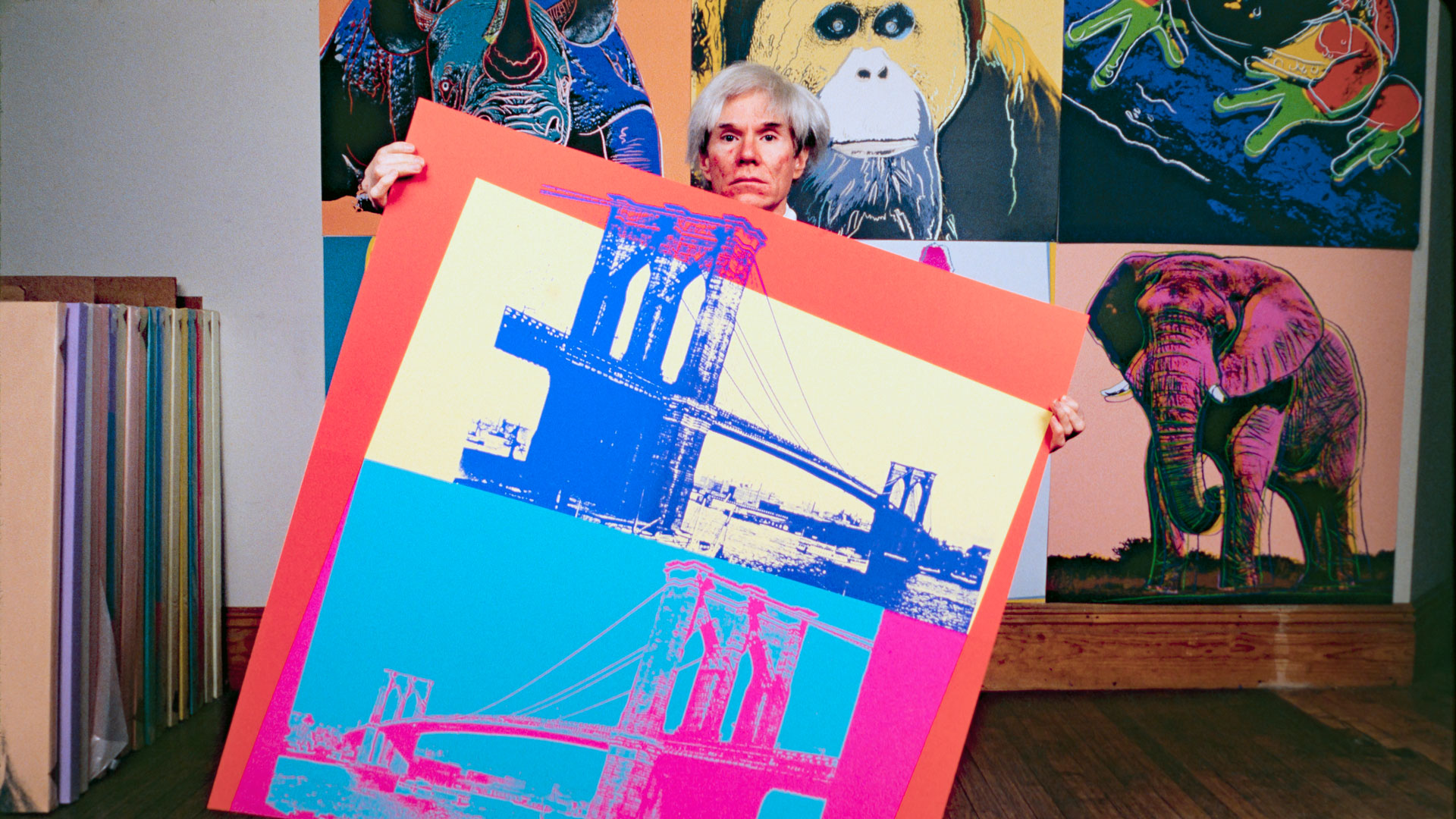 Andy Warhol holding up a painting