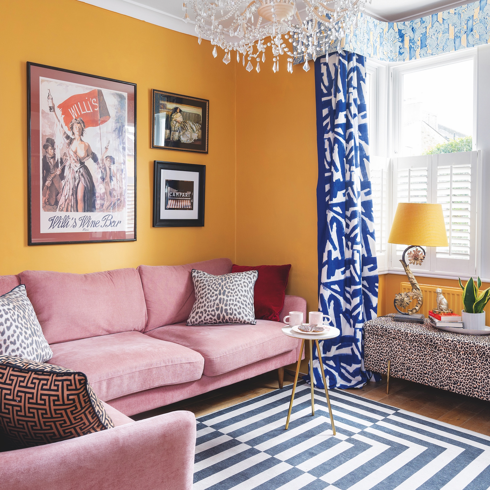 sitting room with yellow painted walls, pink sofa, geometric rug and blue geometric curtains