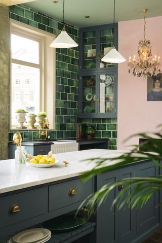 Pink walls in a green kitchen with green tiles by deVOL
