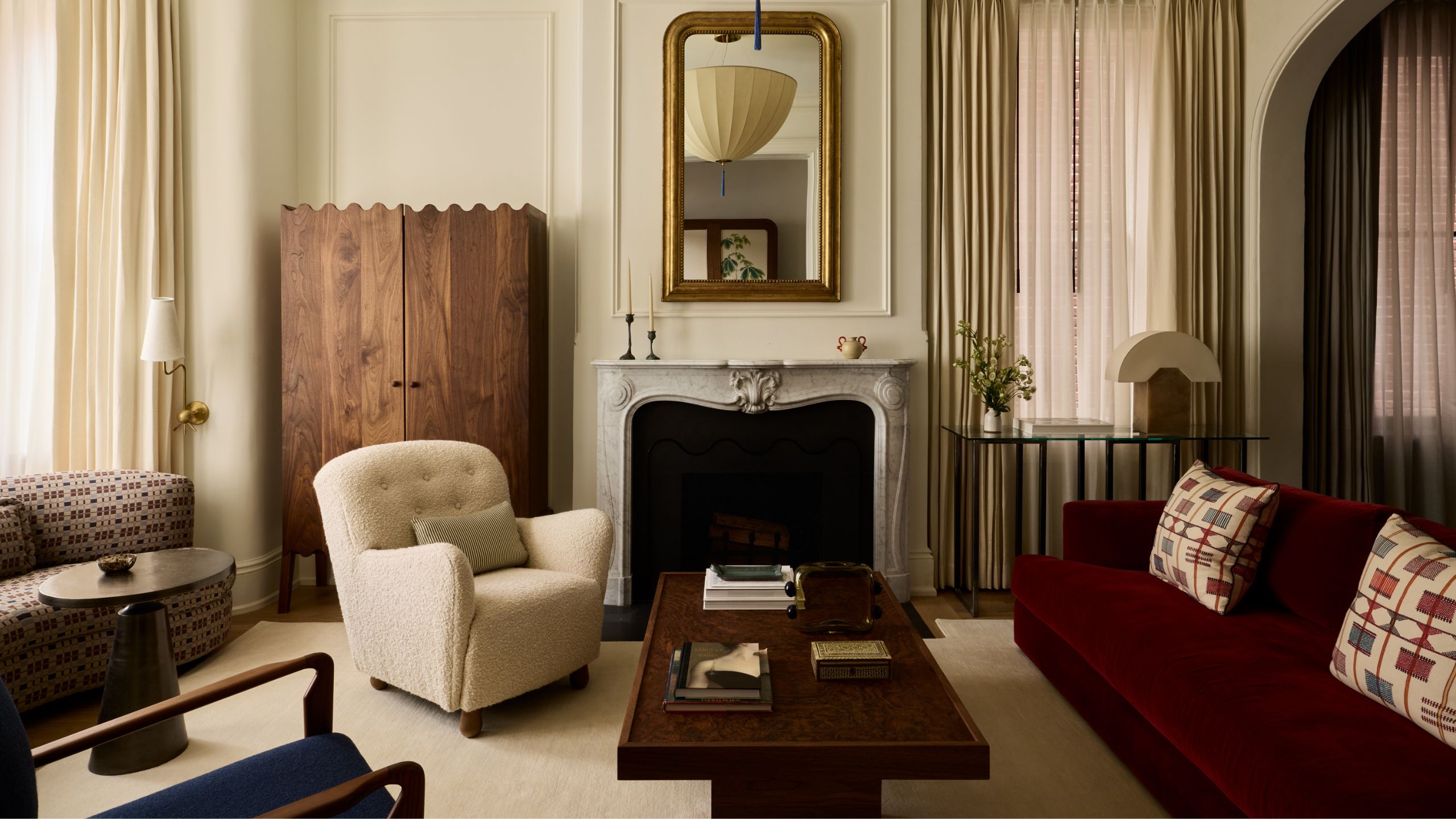 a warm layered living room in a historic Georgetown home with antique fireplace, large windows dressed with neutral drapes and eclectic contemporary furnishings