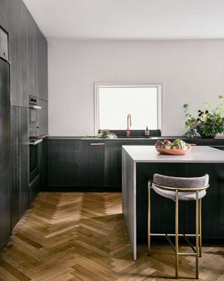 a dark kitchen with a herringbone wooden floor