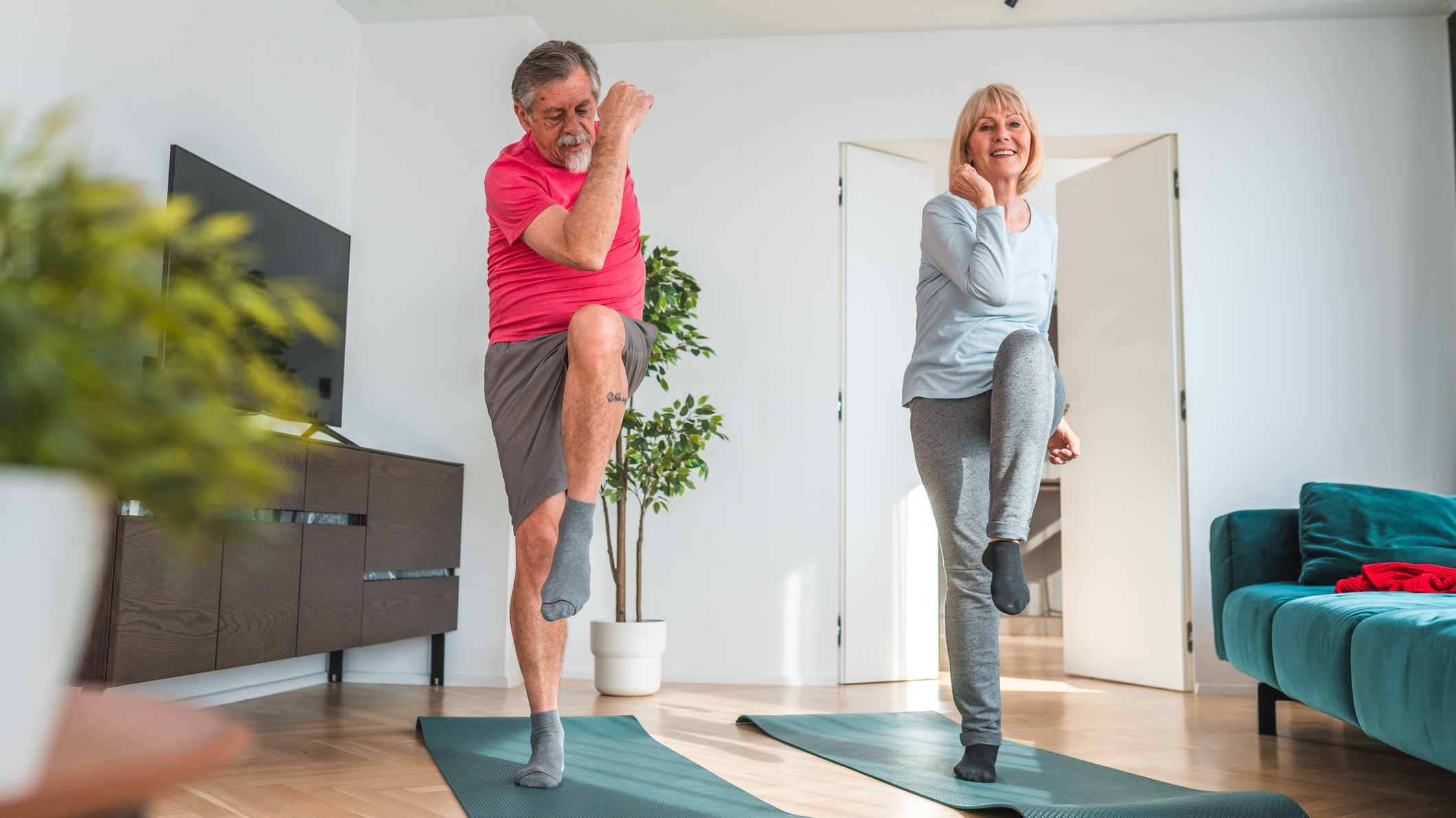 Man and woman exercising in living room, lifting their knees to their elbows