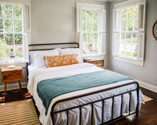 Clean bedroom with well-made bed and with lots of light entering through many windows