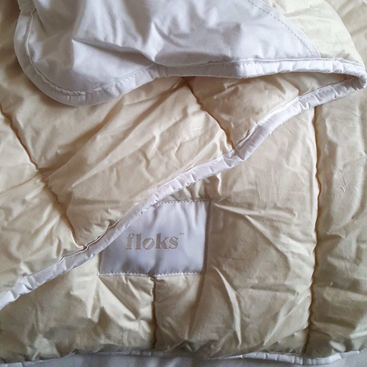 The Floks Luxury British Wool Duvet being tested on a bed with a black headboard