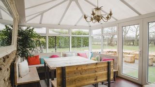 Conservatory interior with wooden seating and table plus colourful cushions