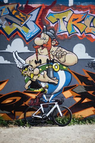 A white bike against a graffiti mural of Asterix and Obelix