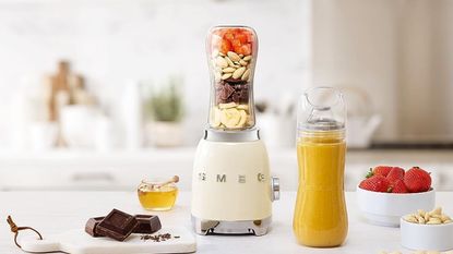 Smeg personal blender on a countertop, full of fruit and nuts