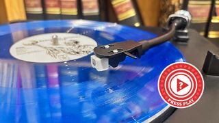Bright blue record sitting on top of a Sharp record player with a press play roundel in the corner