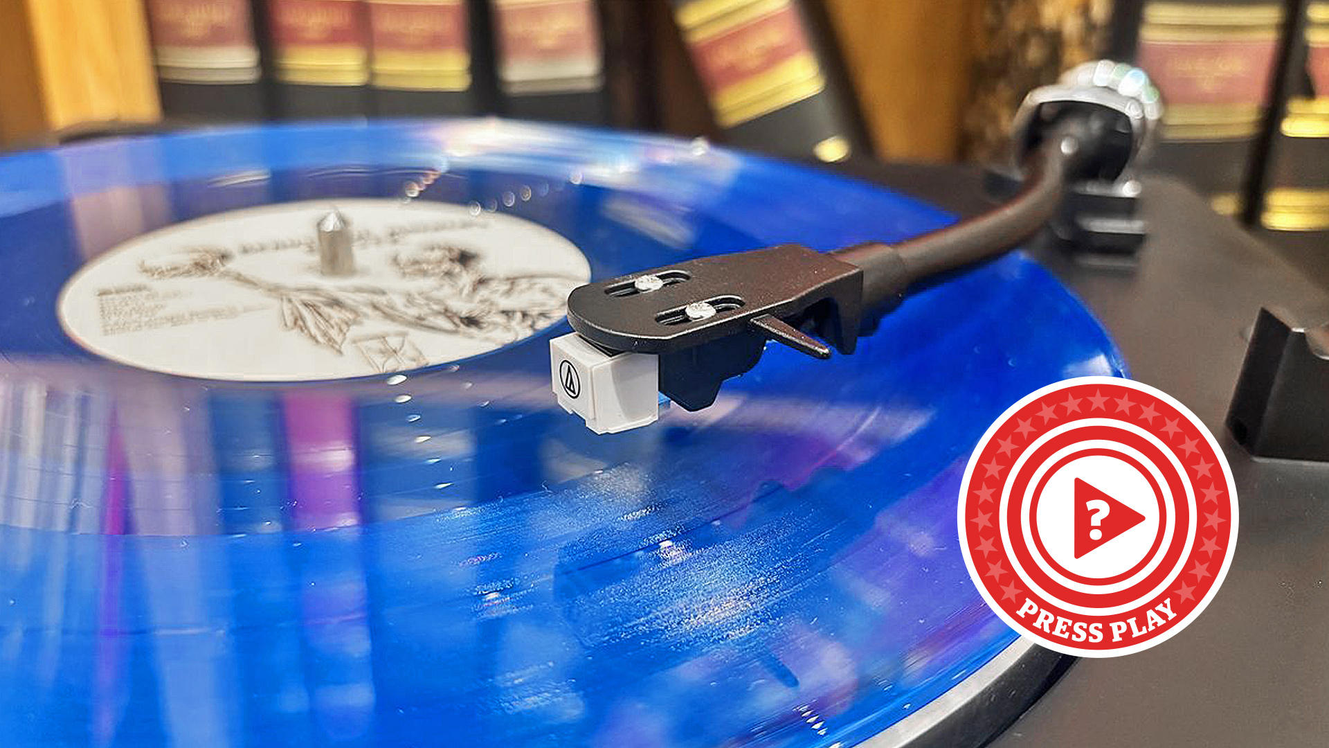 Bright blue record sitting on top of a Sharp record player with a press play roundel in the corner