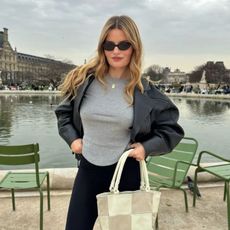 A woman in Paris wearing a black leather jacket with wavy, honey blonde hair