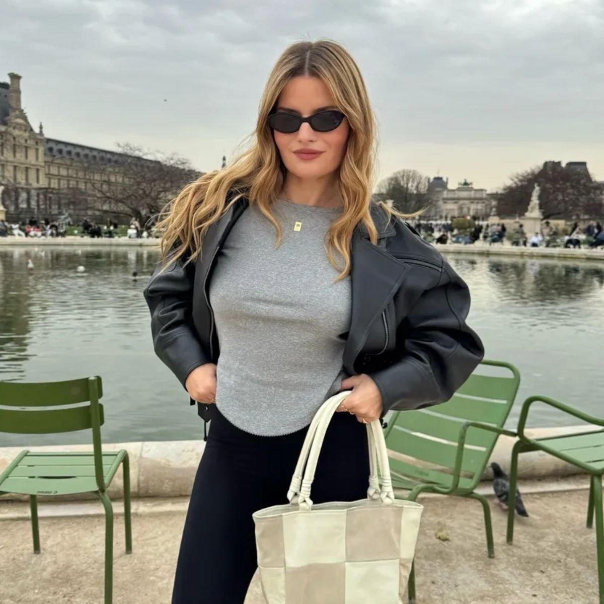 A woman in Paris wearing a black leather jacket with wavy, honey blonde hair