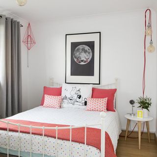 white bedroom with wrought iron bed, artwork and wall light