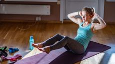 A woman completing a core workout on a yoga mat in her living room 