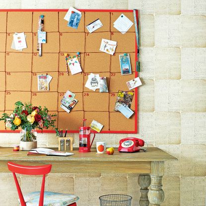 Wooden desk below large cork pinboard calender