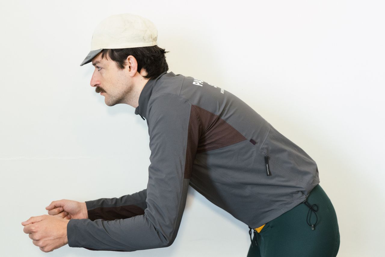 A white man in a grey jacket simulates different riding positions