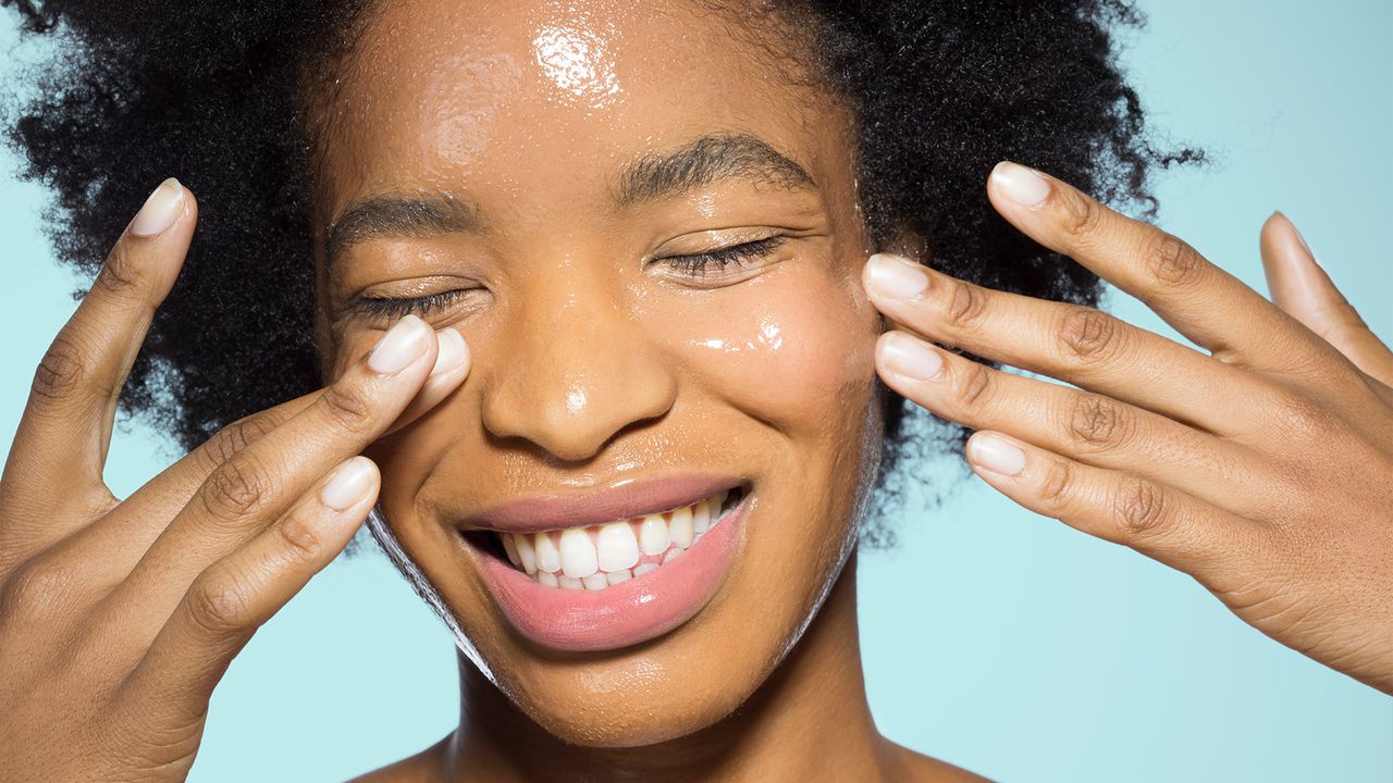 Young female applying glossy make-up - stock photo