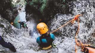 A woman prepares to rappell into water in a canyon