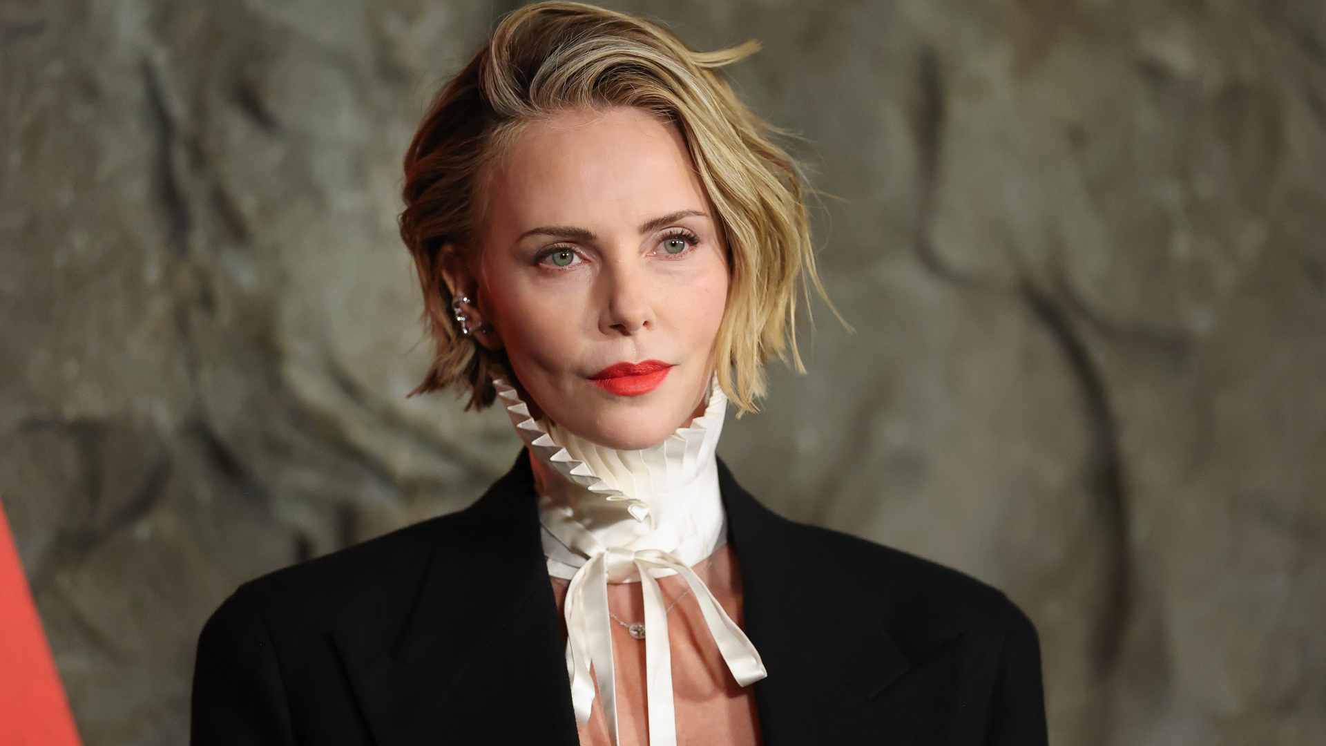 Charlize Theron wearing a black blazer and white collar