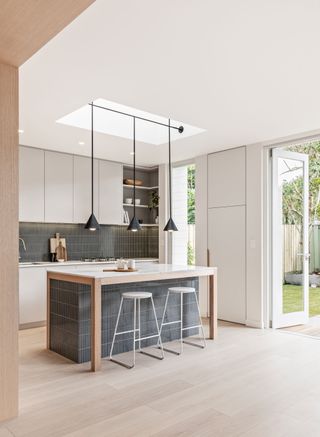 a modern kitchen extension with hanging lighting extending from the skylight above the kitchen island