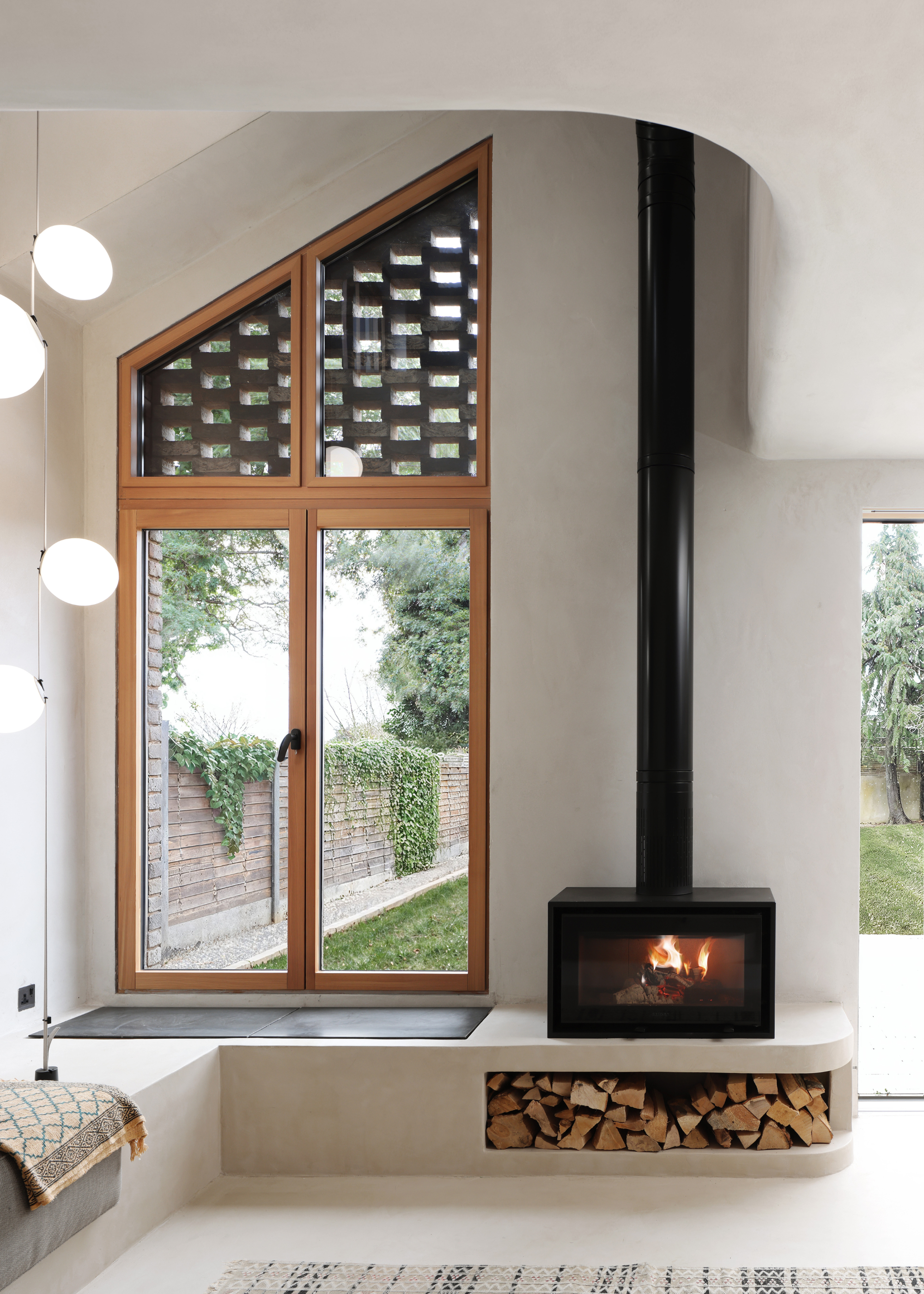 a curving room with plastered walls and a small black fireplace